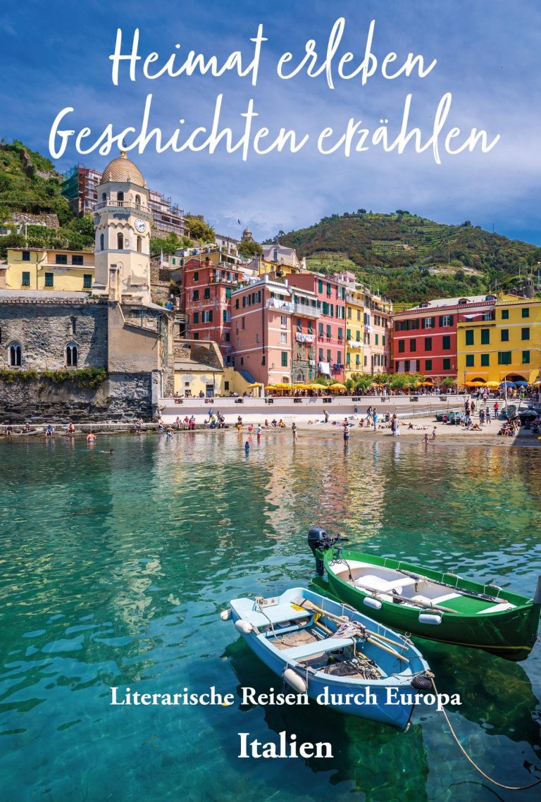 Blühende Wiese mit Bergen im Hintergrund und einer italienischen Flagge.